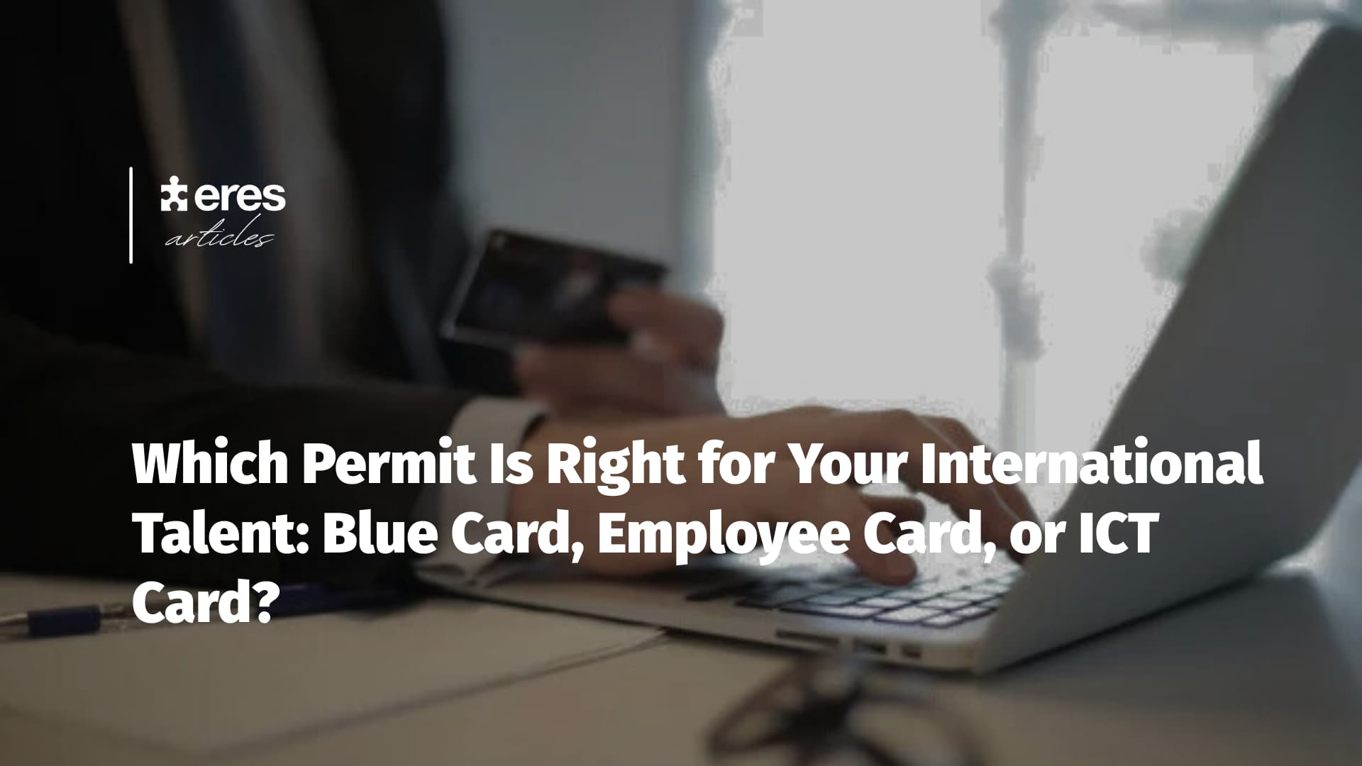 HR Manager working on a laptop and holding a card - International Talent Permits